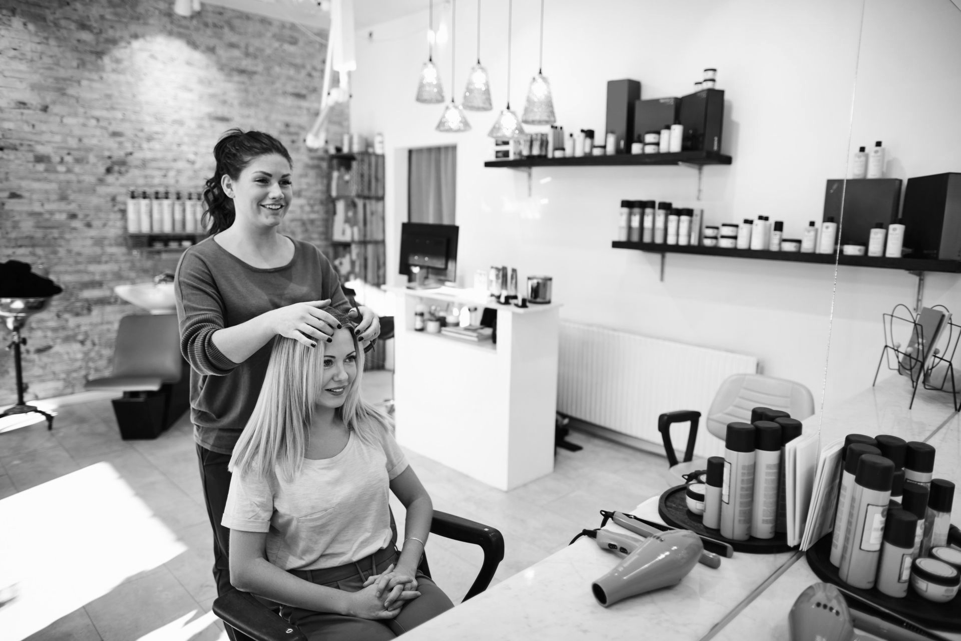 Hairdresser styling client's short brown hair with a flat iron in a salon.