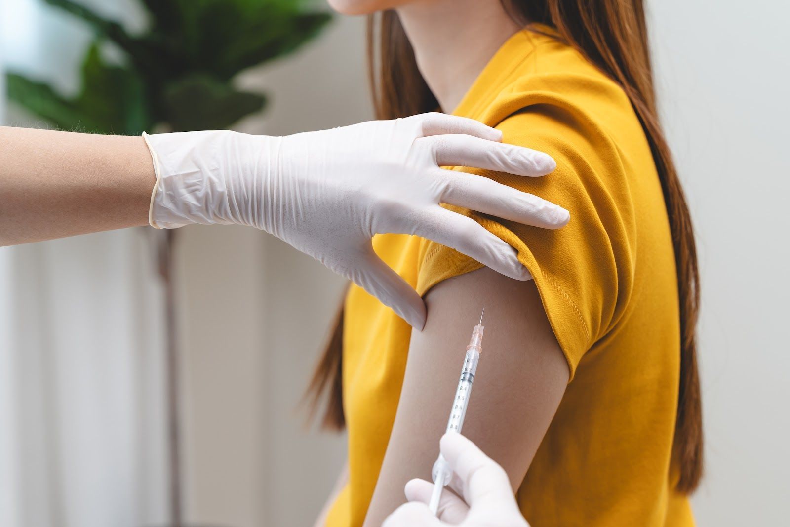 Person receiving a vaccination shot in arm; medical professional in gloves.