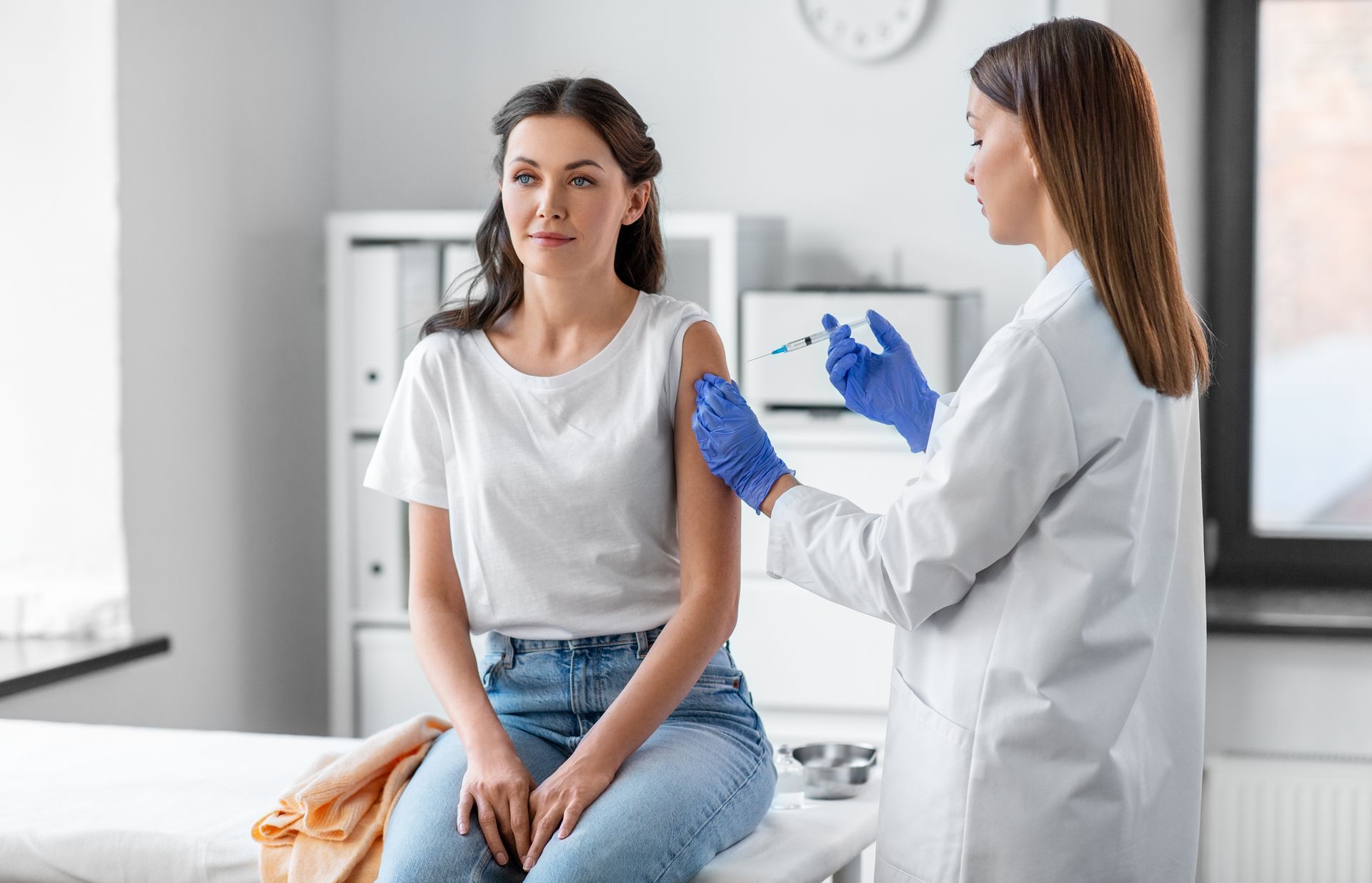 A doctor is giving a woman an injection in her arm.