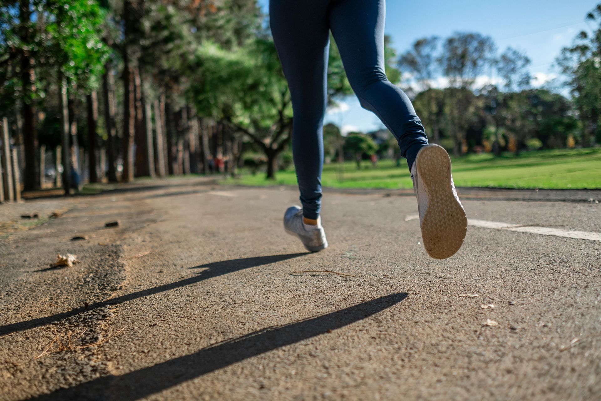 A person is running down a road in a park.