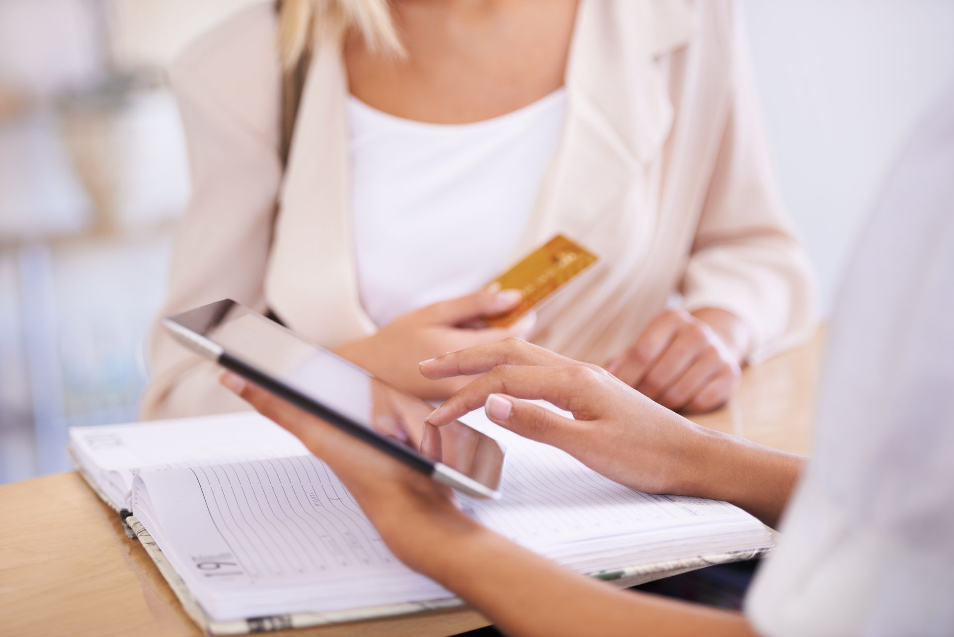 A woman is holding a credit card and using a tablet