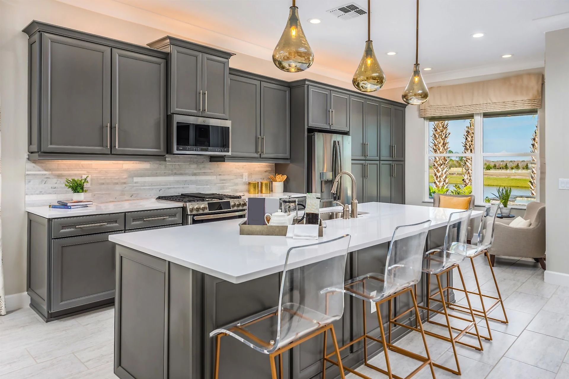 A kitchen with gray cabinets , white counter tops , and a large island.