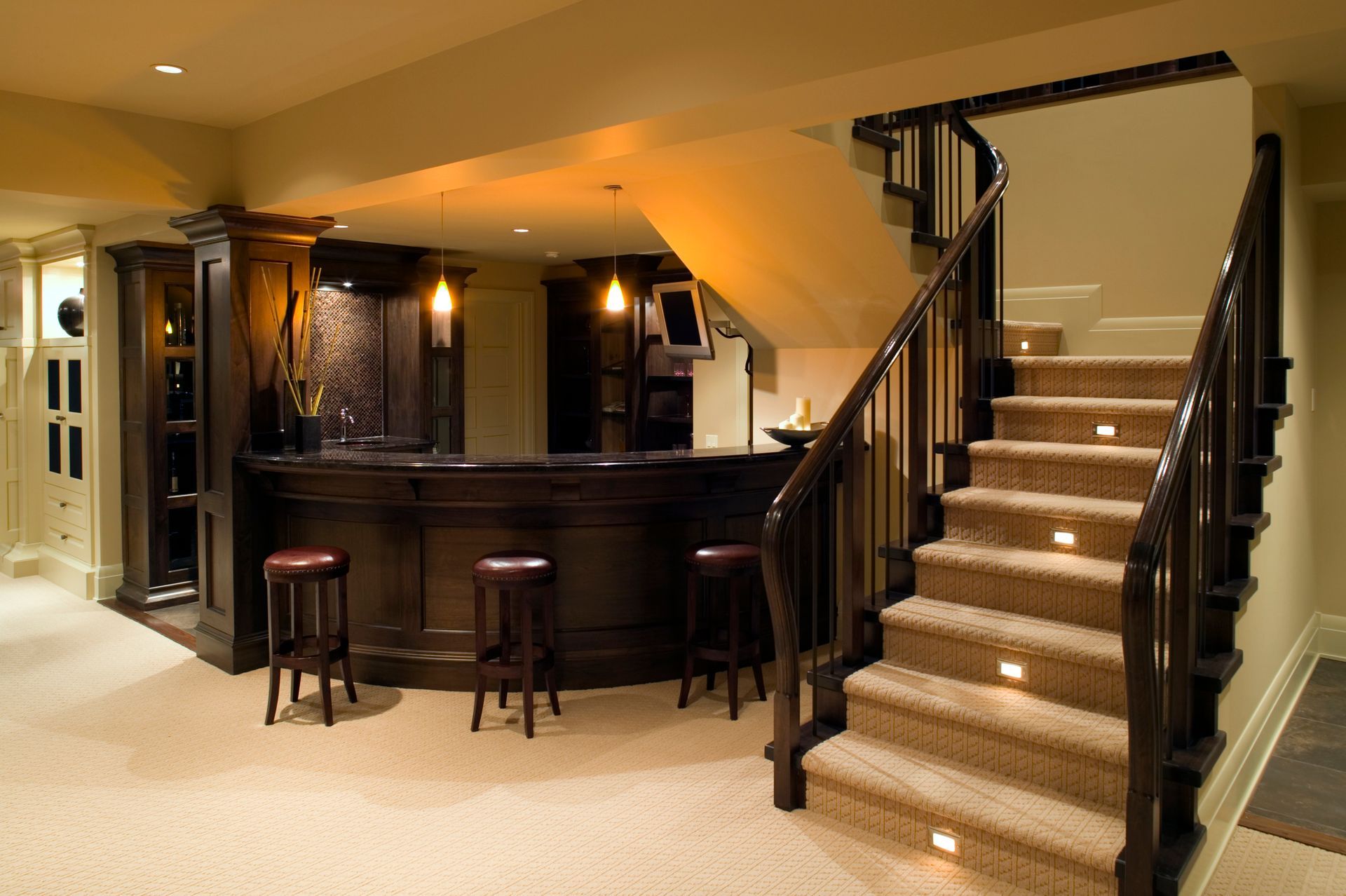 A basement with a bar and stairs leading up to the second floor