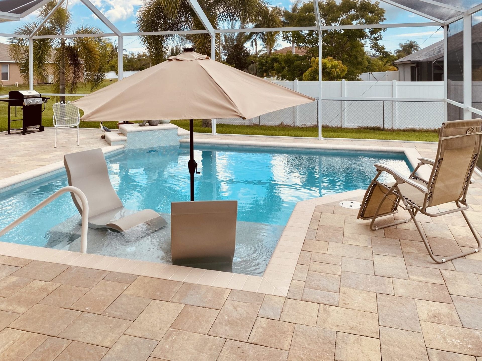 A swimming pool with chairs and an umbrella in it