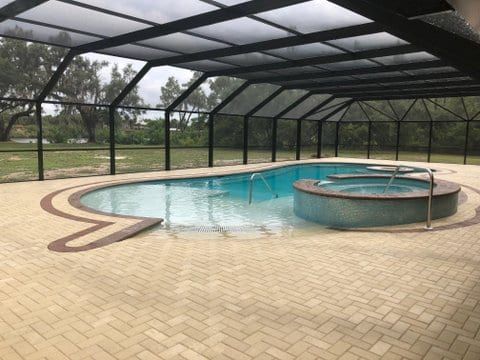 A large swimming pool with a hot tub underneath it