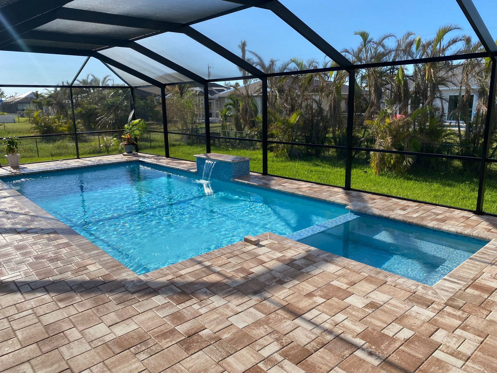 A large swimming pool is surrounded by a screened in area.