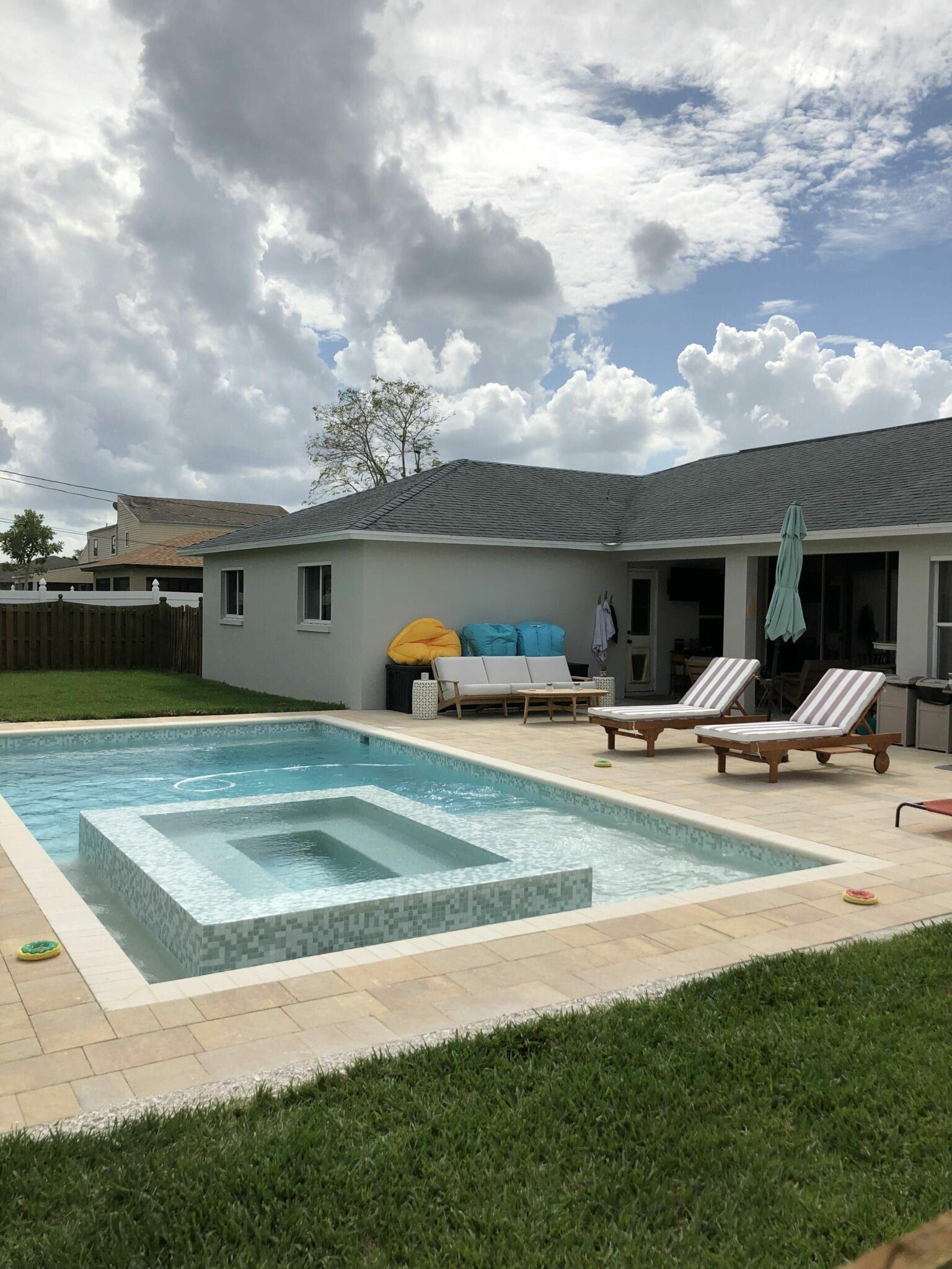 A large swimming pool is in the backyard of a house.