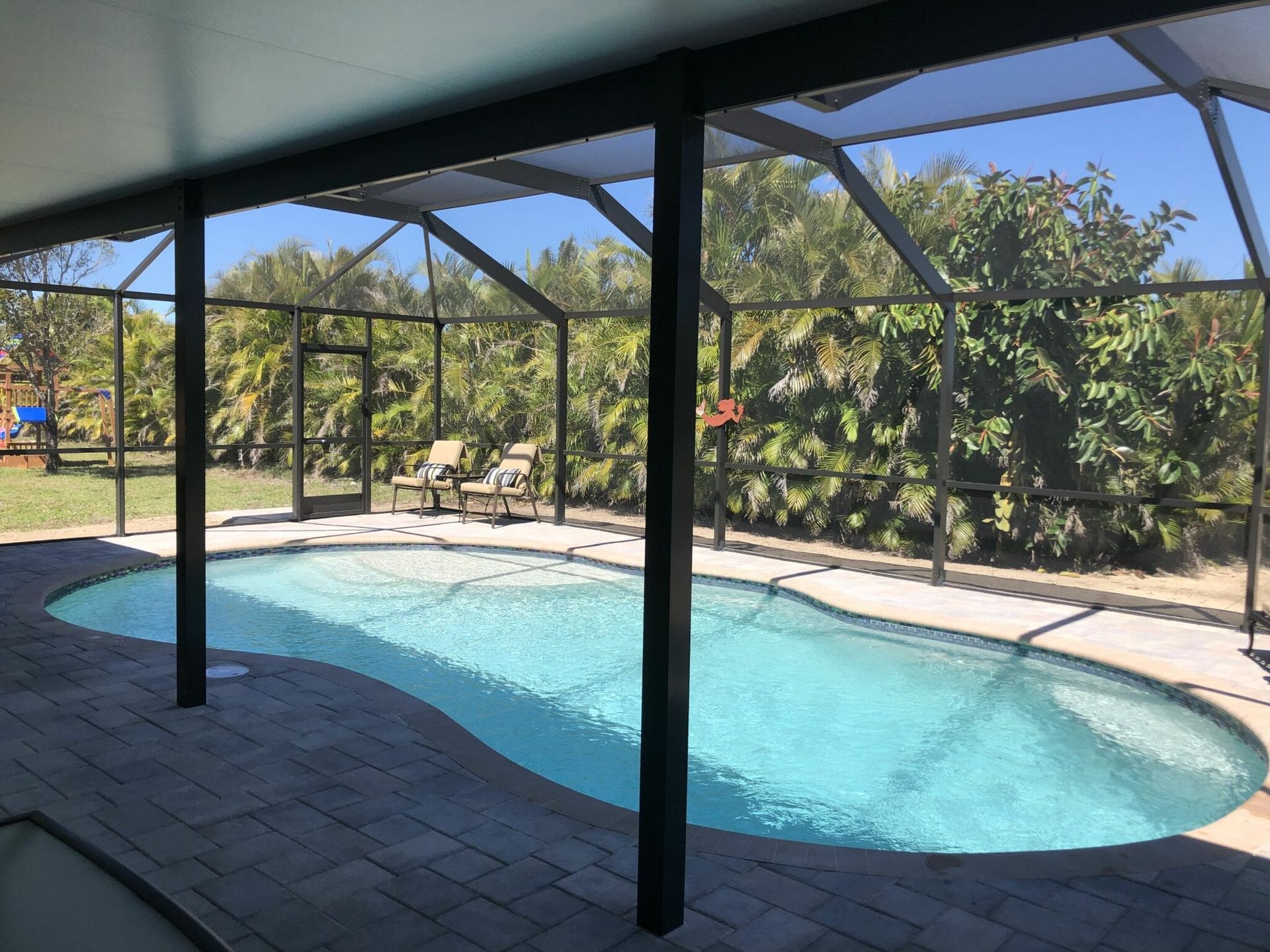 A large swimming pool is covered by a screened in area built by Into h2o Pools & Spas Cape Coral
