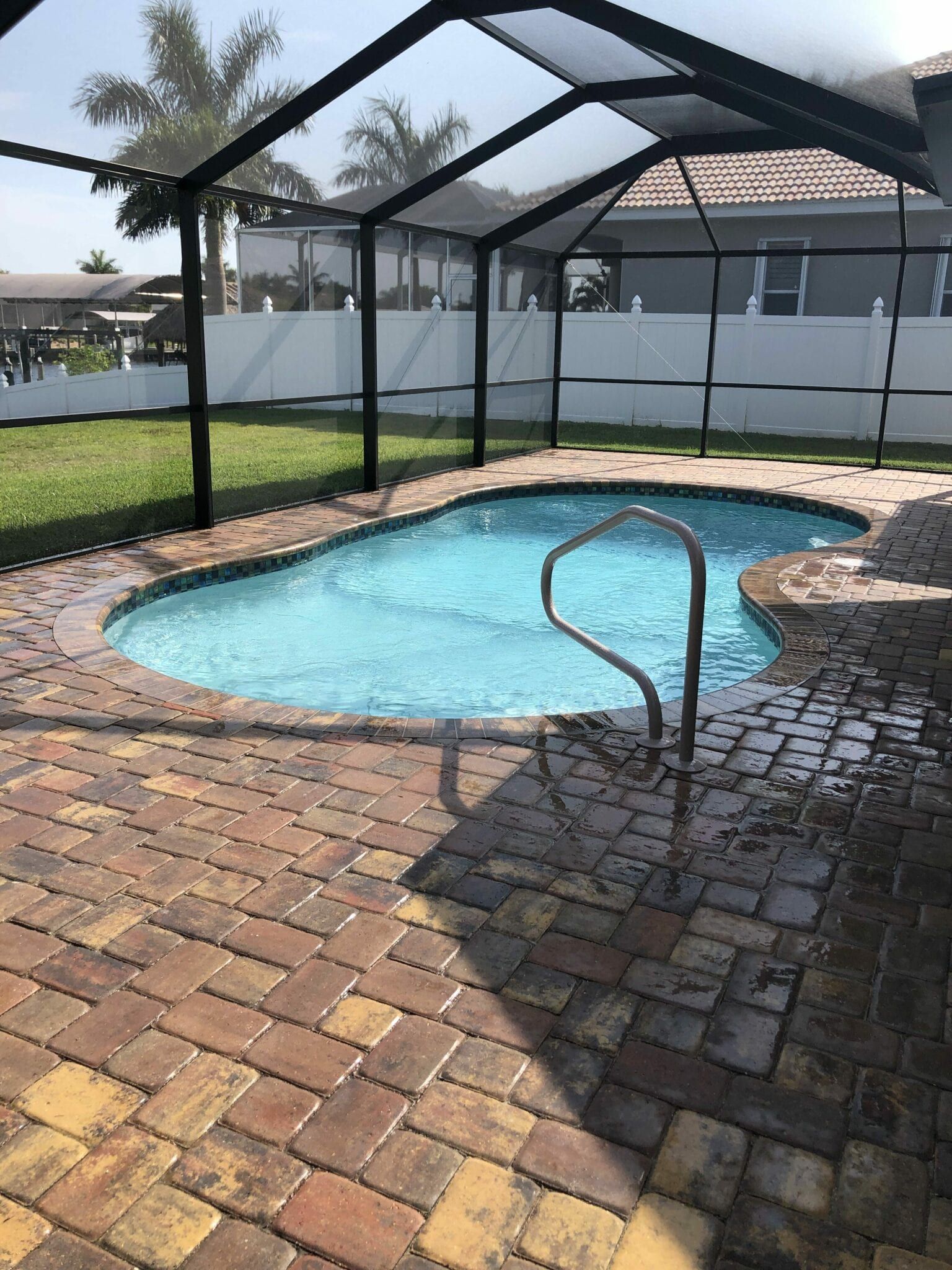 A large swimming pool is surrounded by a screened in area built by Into h2o Pools & Spas Cape Coral