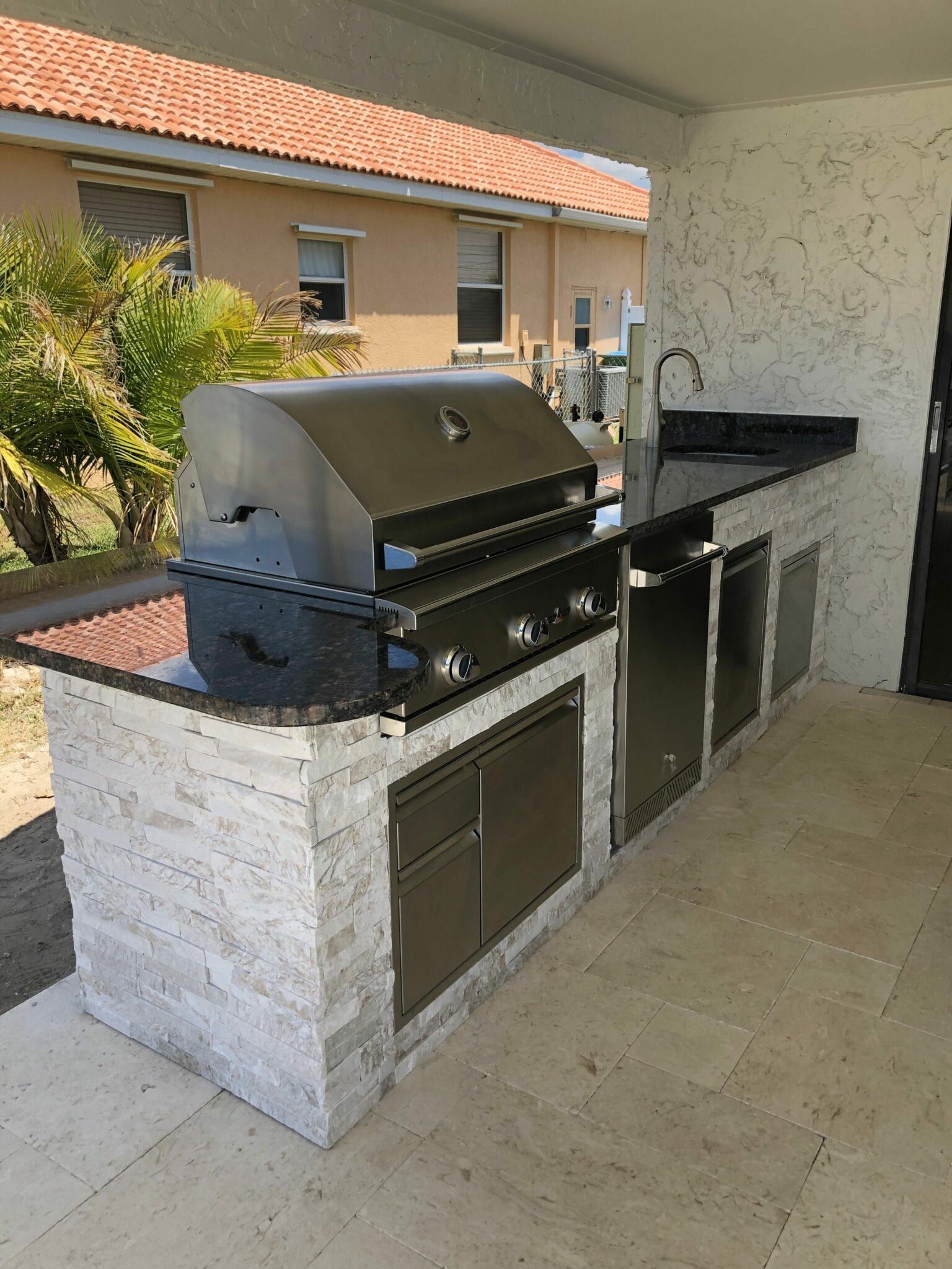 A large outdoor kitchen with a grill and sink. built by Into h2o Pools & Spas Cape Coral