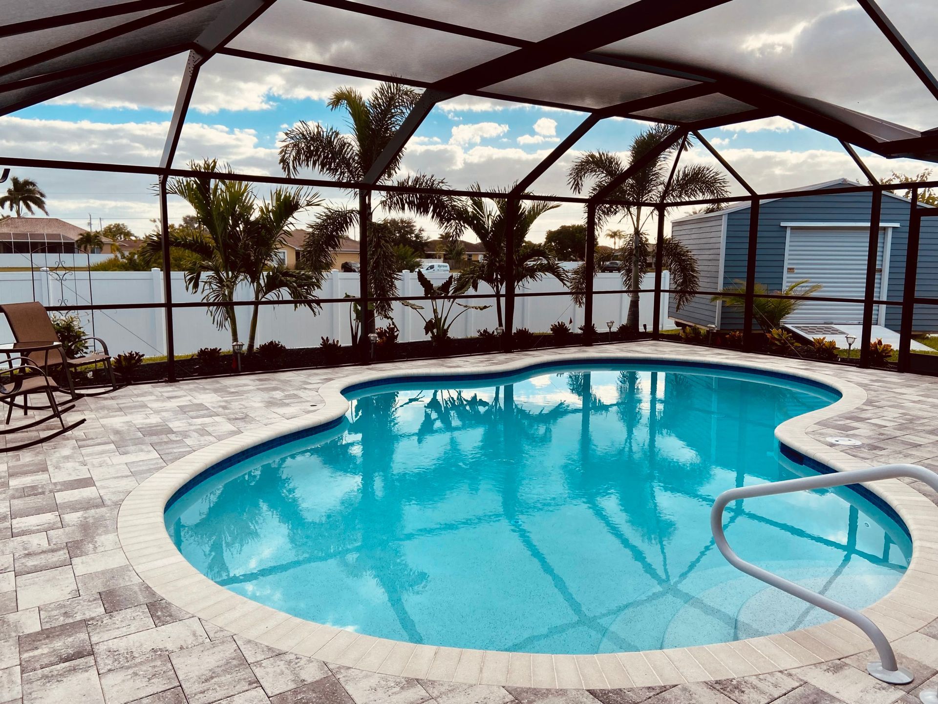 A large swimming pool is surrounded by a screened in area built by Into h2o Pools & Spas Cape Coral