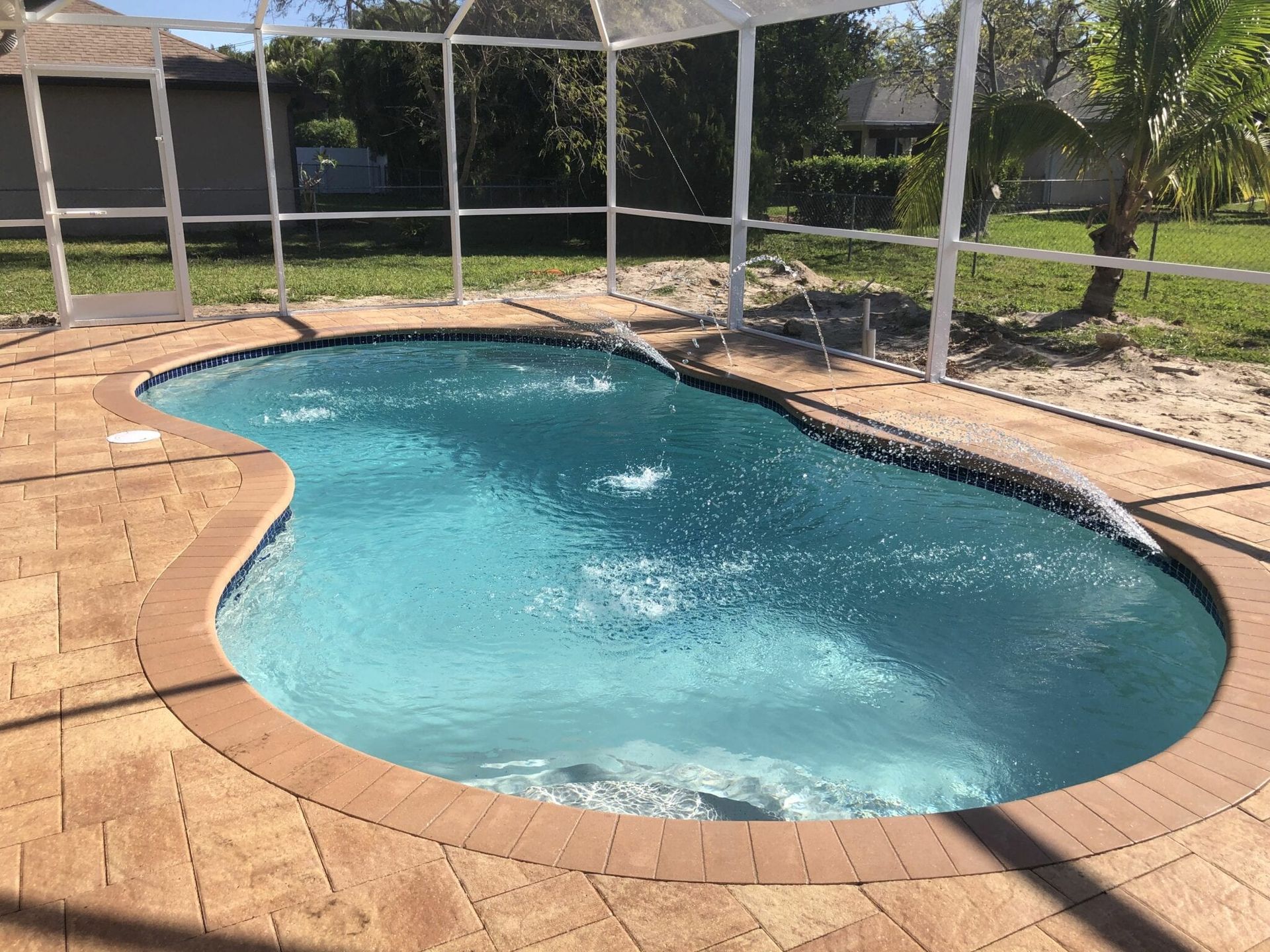 A large swimming pool is surrounded by a screened in area built by Into h2o Pools & Spas Cape Coral