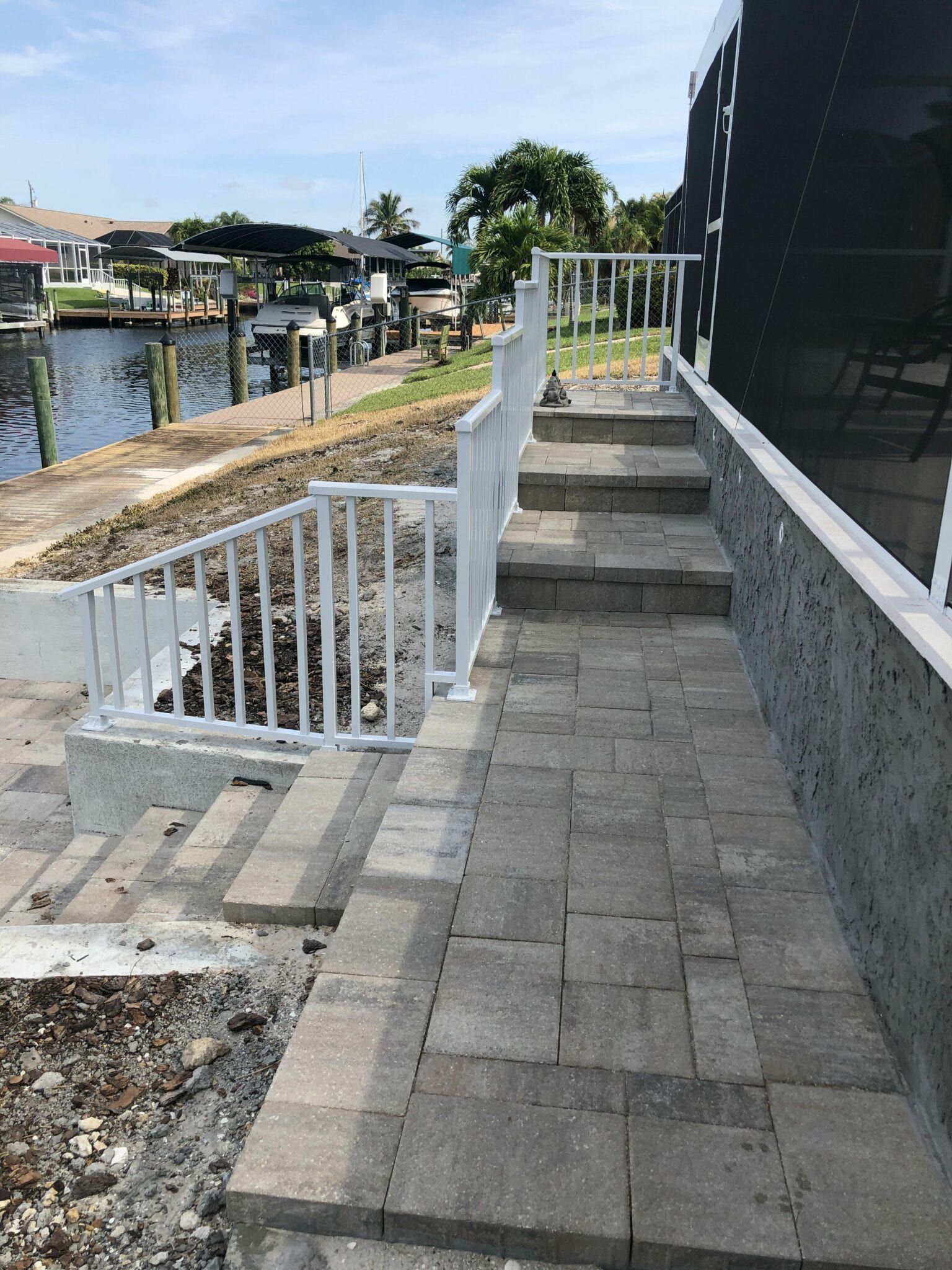 A set of stairs leading up to a dock with a white railing built by Into h2o Pools & Spas Cape Coral