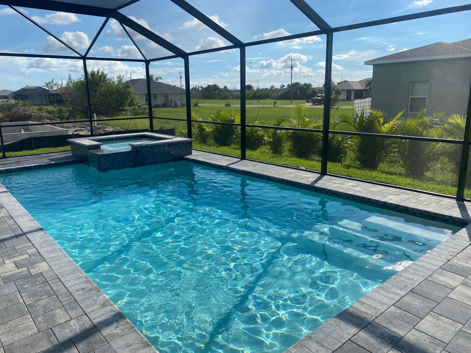 A large swimming pool is surrounded by a screened in area built by Into h2o Pools & Spas Cape Coral
