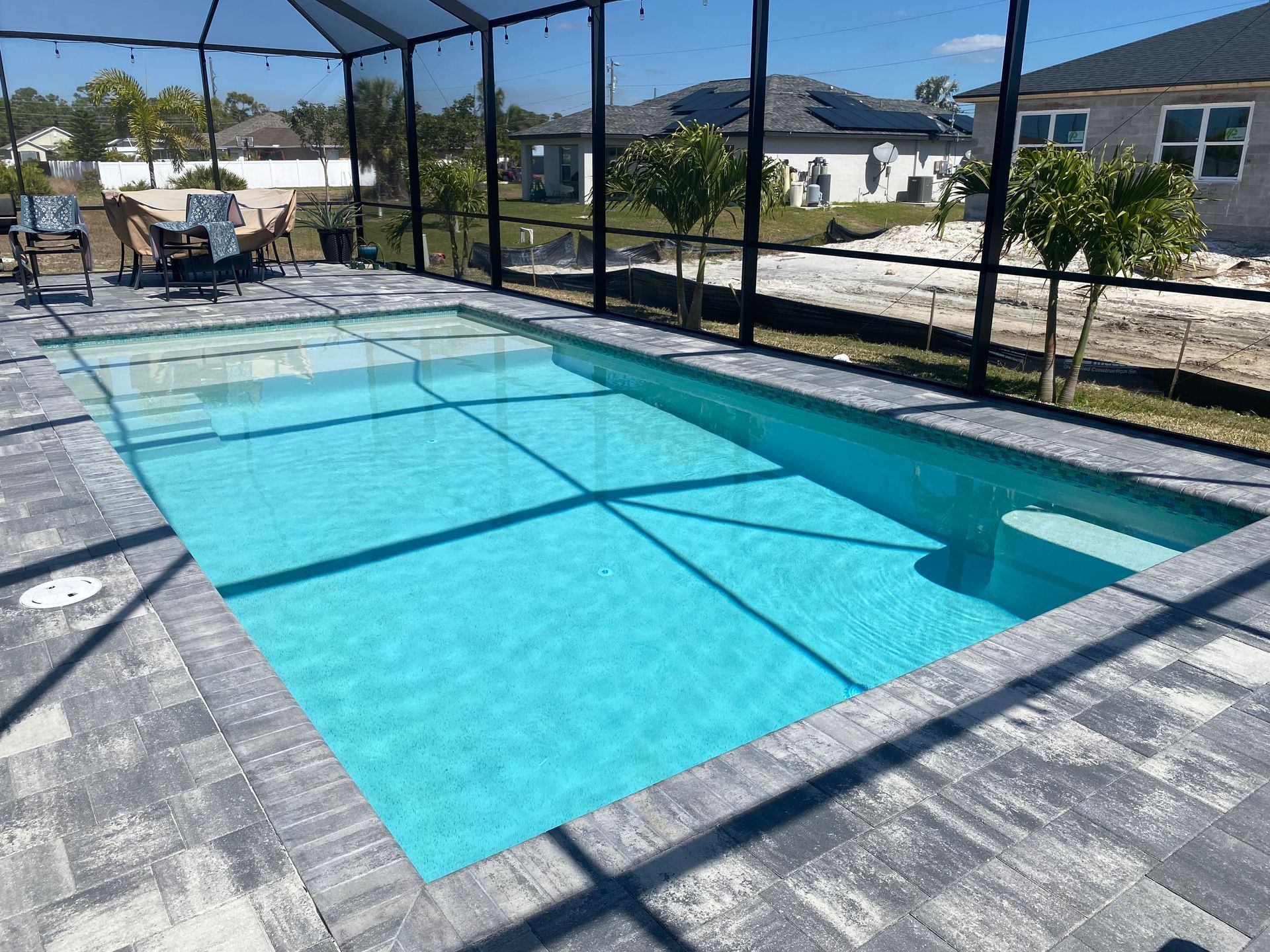 A large swimming pool is surrounded by a screened in area built by Into h2o Pools & Spas Cape Coral