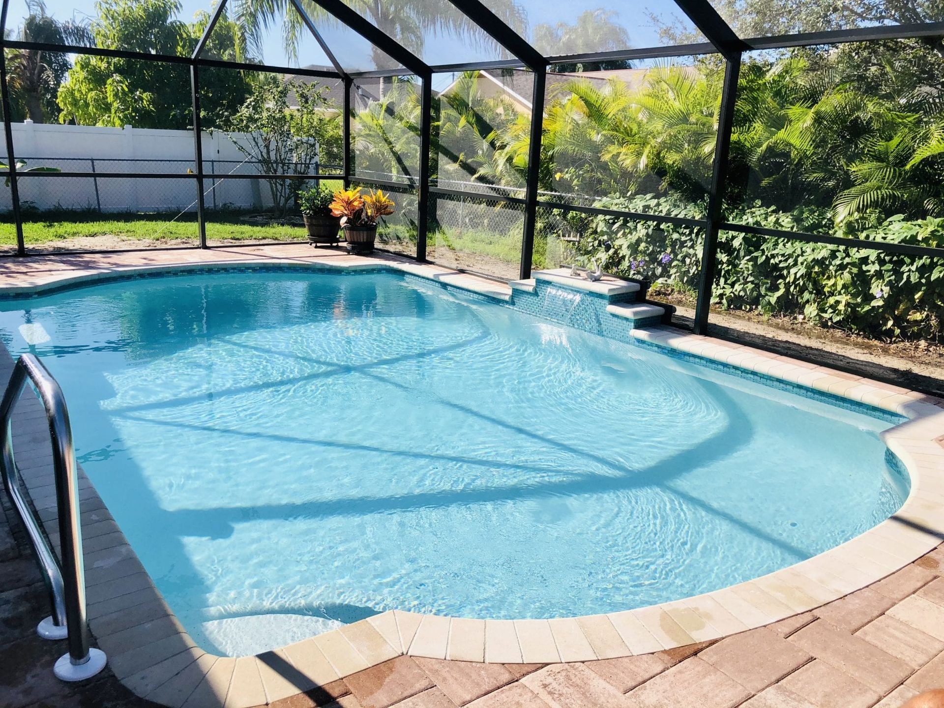 A large swimming pool is surrounded by a screened in area built by Into h2o Pools & Spas Cape Coral