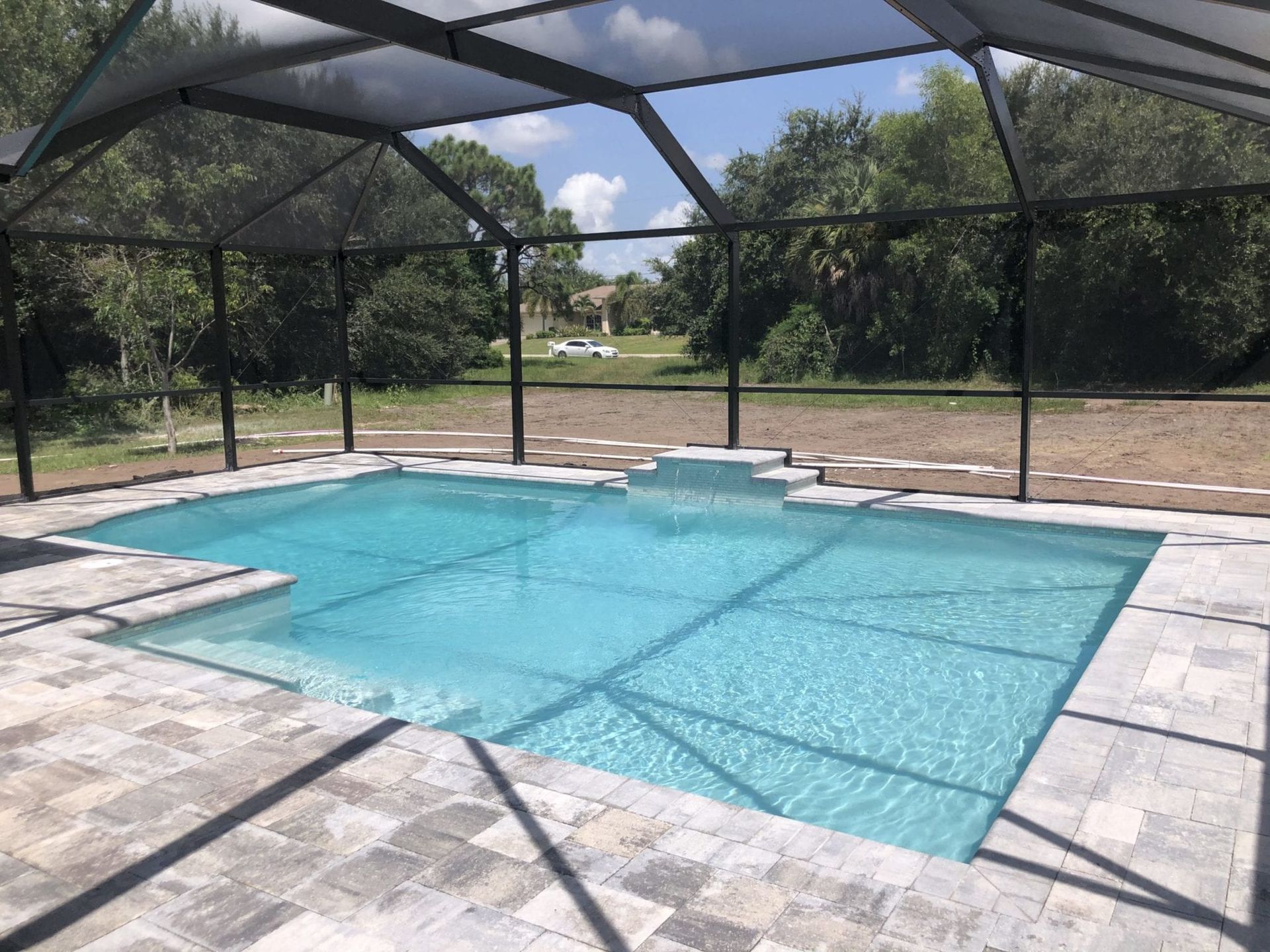 A large swimming pool is under a screened in area built by Into h2o Pools & Spas Cape Coral