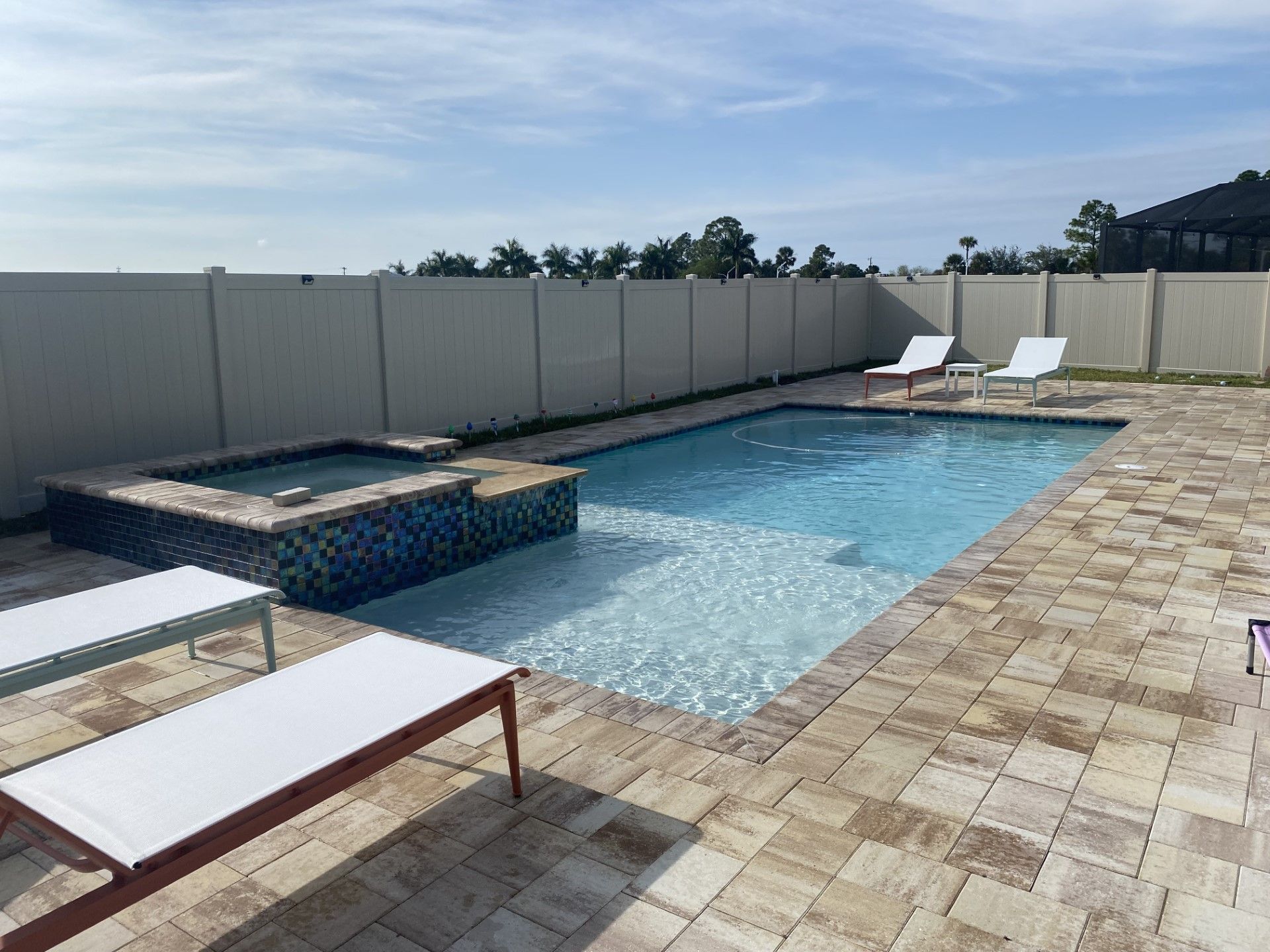 A large swimming pool surrounded by chairs and a fence built by Into h2o Pools & Spas Cape Coral