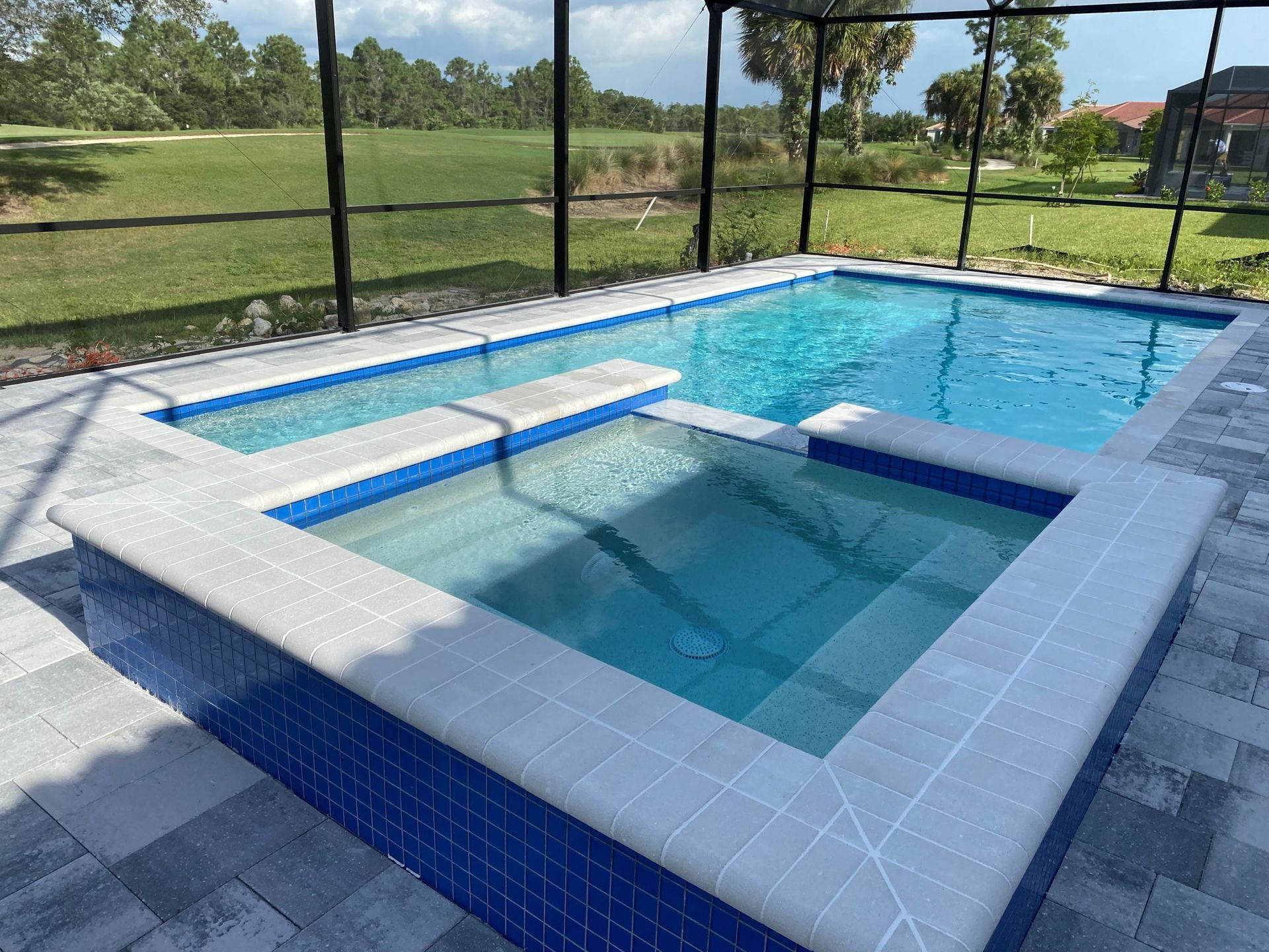 A large swimming pool with a hot tub in the middle of it built by Into h2o Pools & Spas Cape Coral