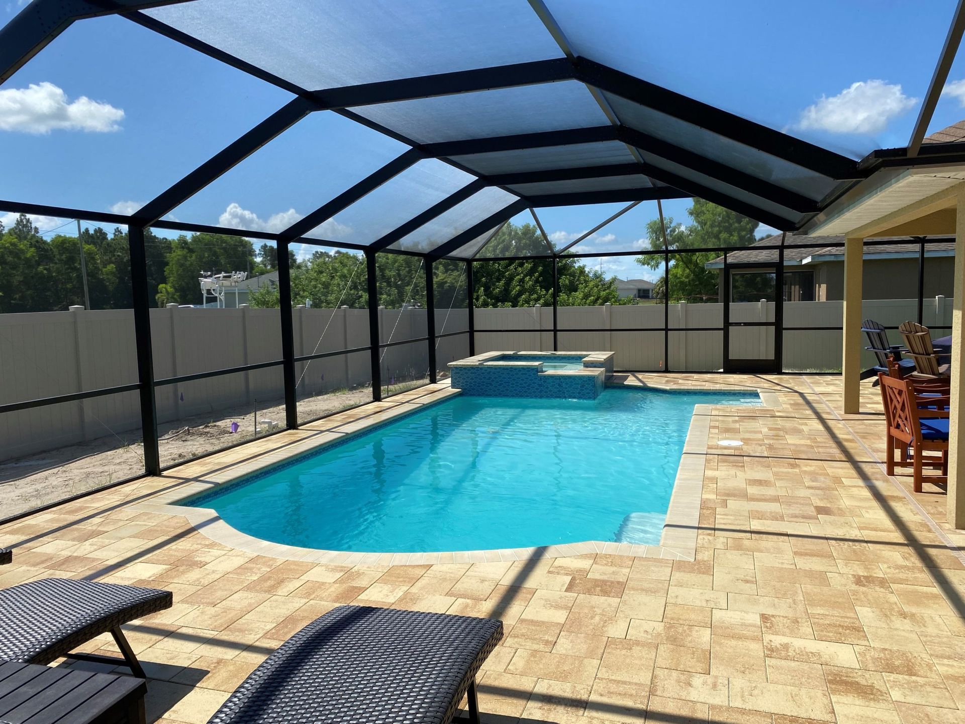 A large swimming pool is surrounded by a screened in area built by Into h2o Pools & Spas Cape Coral