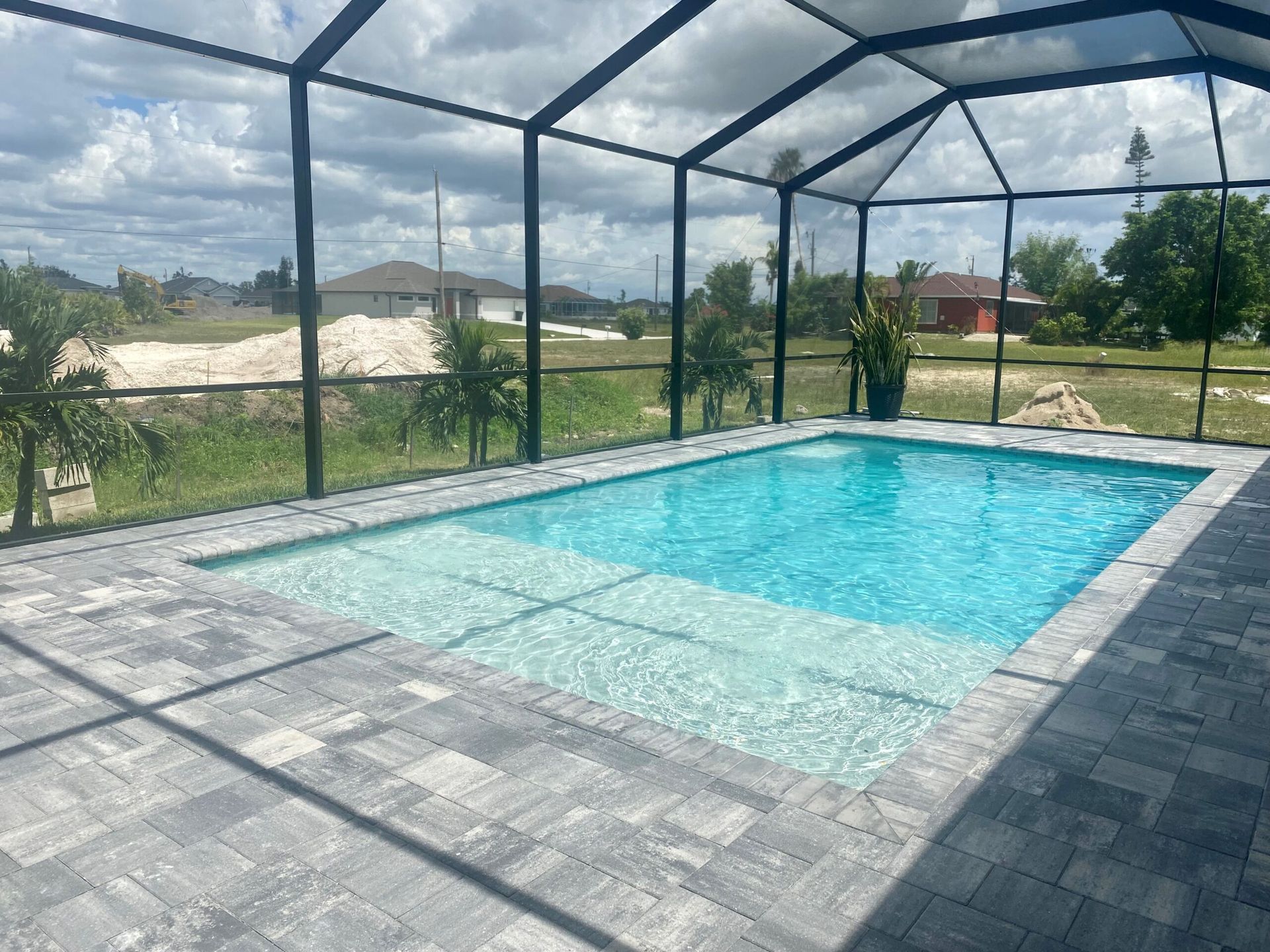 A large swimming pool is surrounded by a screened in area built by Into h2o Pools & Spas Cape Coral