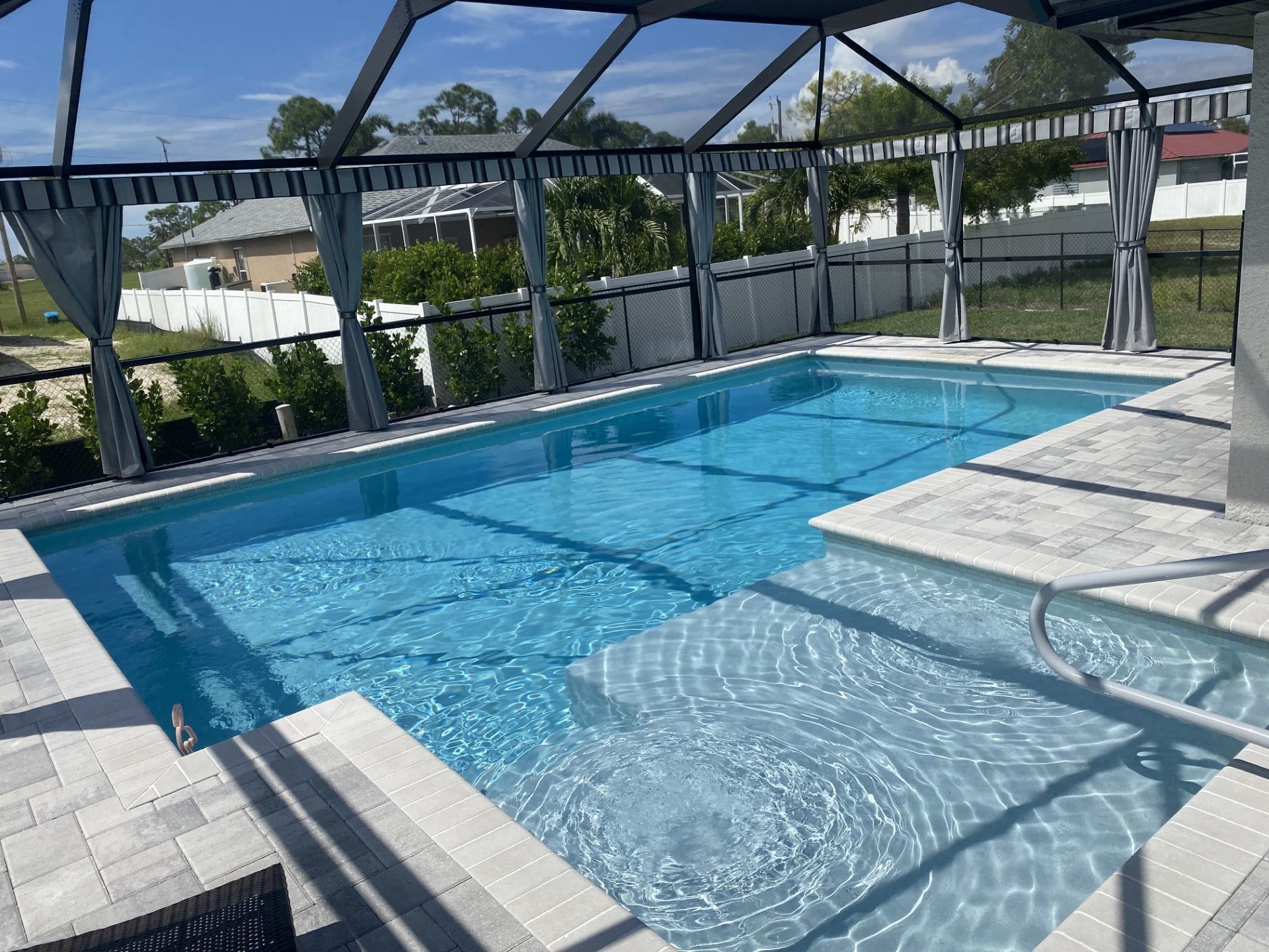 A large indoor swimming pool surrounded by a screened in area built by Into h2o Pools & Spas Cape Coral