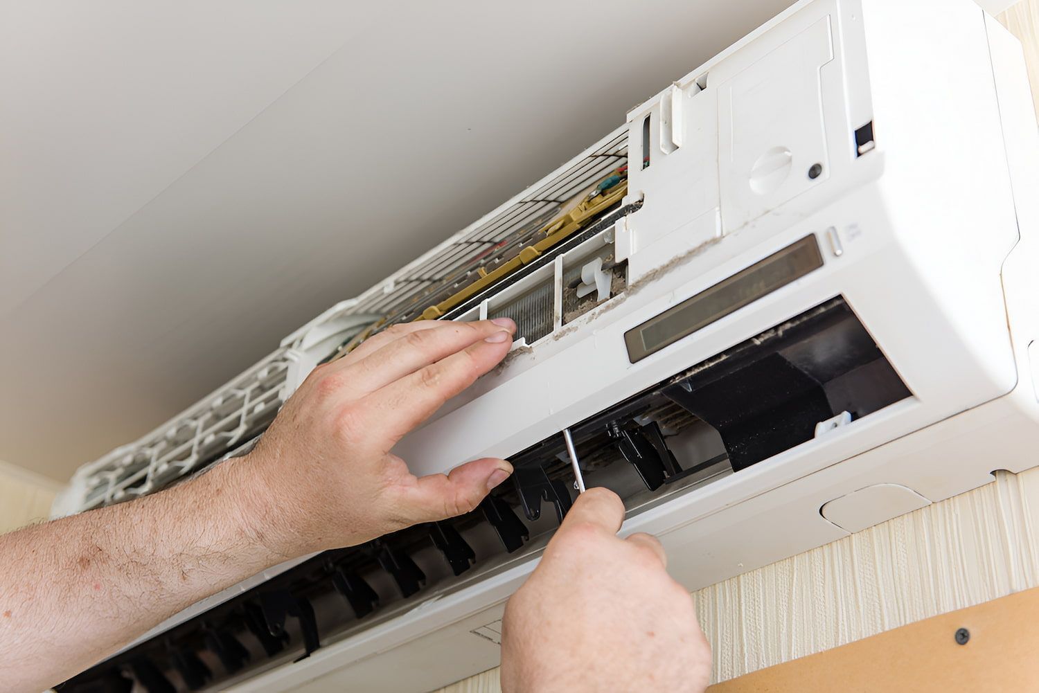 Person Repairing a White Air Conditioner Unit Mounted on a Wall — Frosty Solutions Air Conditioning In Mudgee, NSW