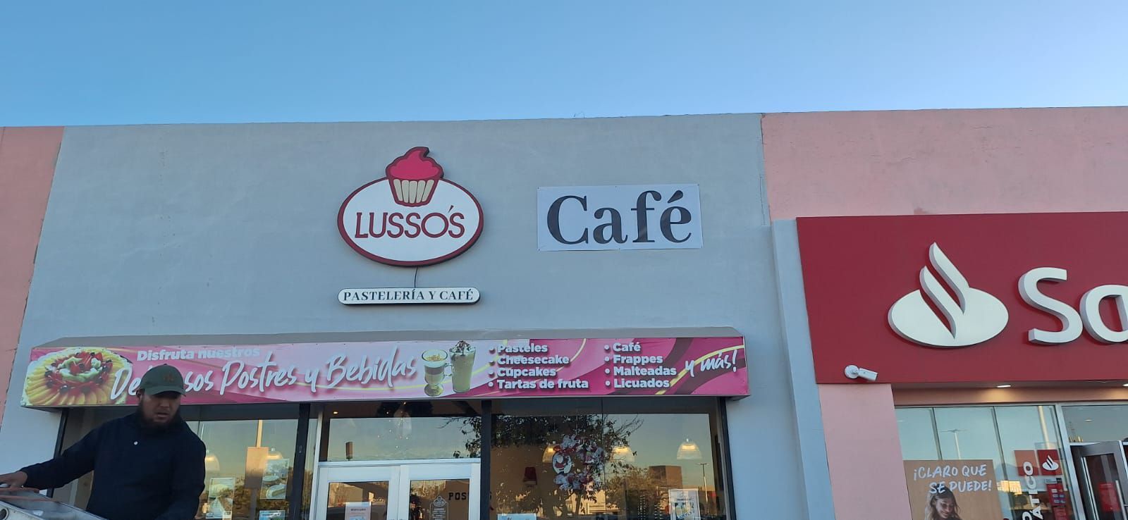 Fachada de la panadería Café Lussos con el logo de cupcakes, al lado del banco Santander.
