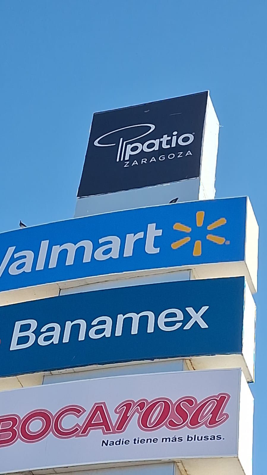 Letreros de Patio Tlaxcala, Walmart, Banamex y Bocaroza contra un cielo azul.