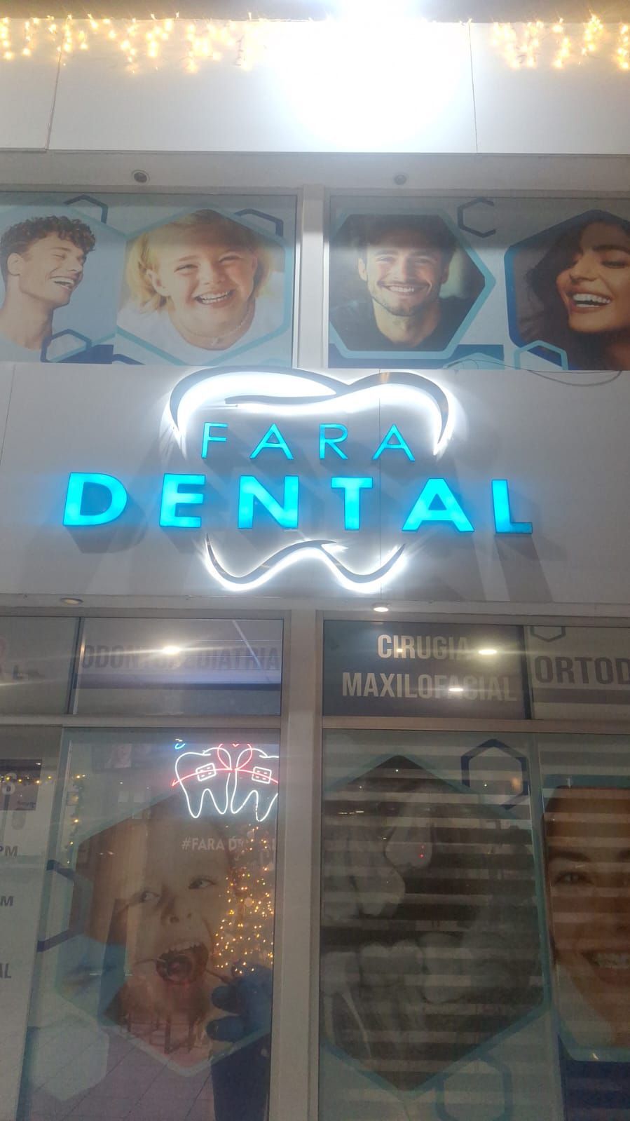 Letrero de Fara Dental con el logotipo de un diente y caras de personas sobre la ventana.