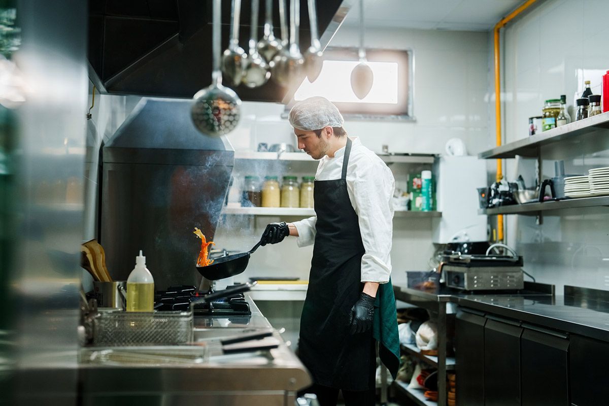 Uno chef sta cucinando in una cucina commerciale.