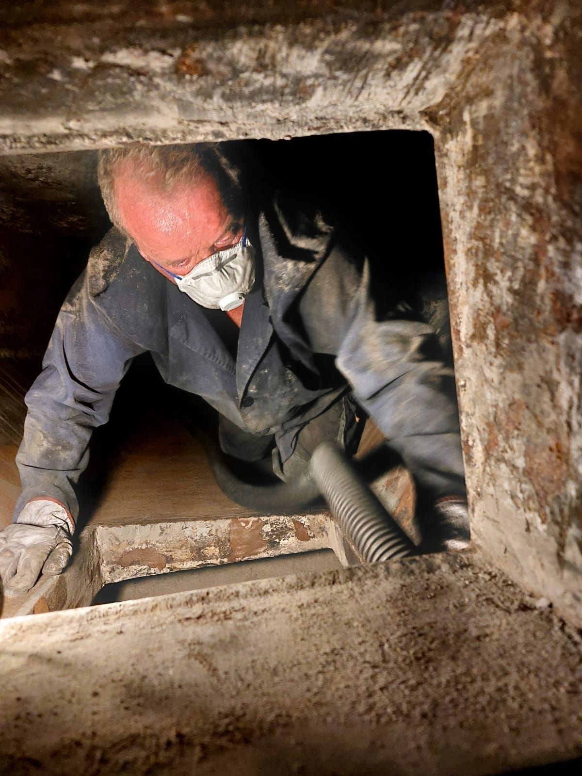 Spazzacamino che indossa una maschera sta lavorando sta pulendo un condotto