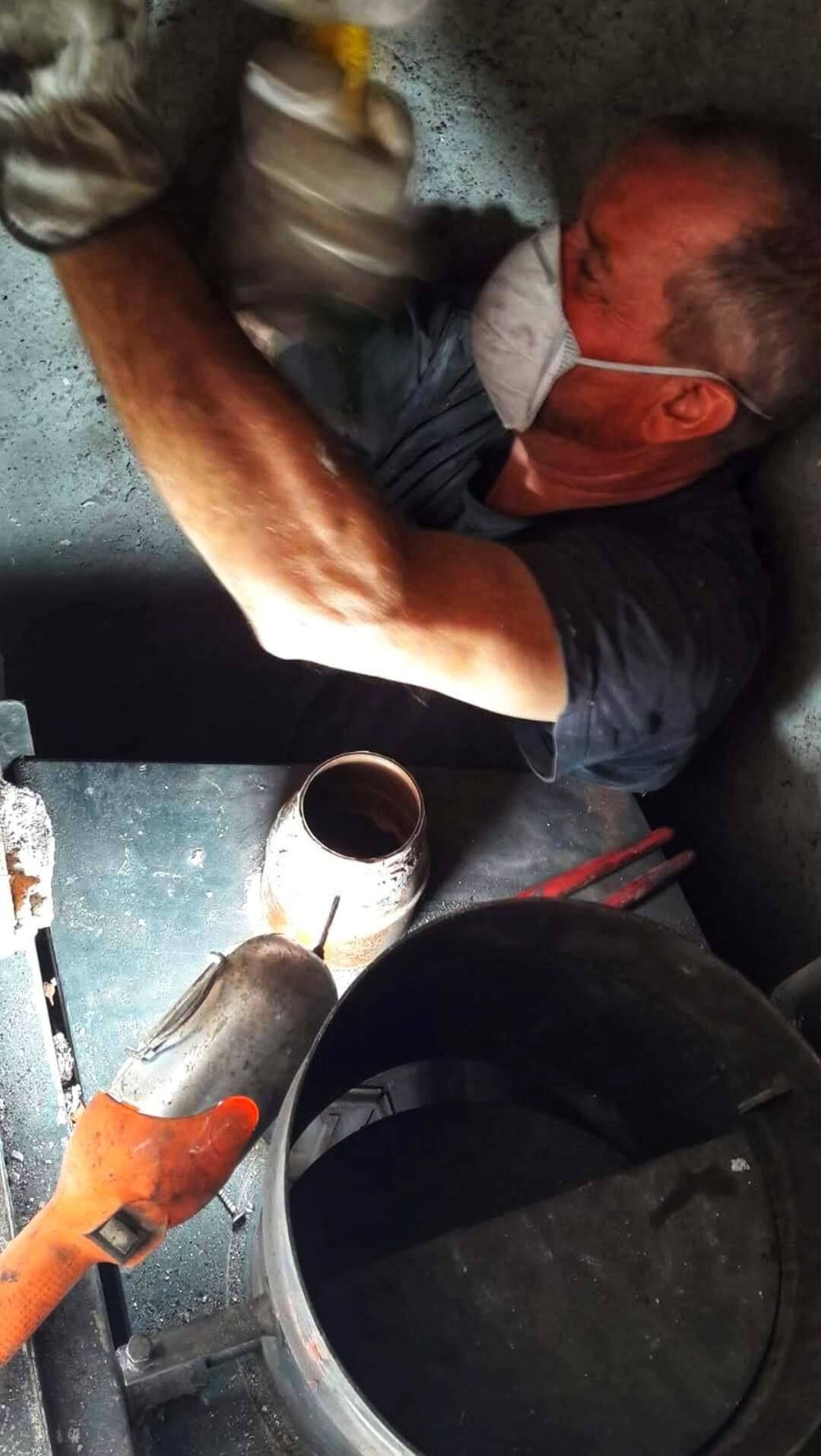 spazzacamino che indossa una maschera e dei guanti sta lavorando su un tubo.