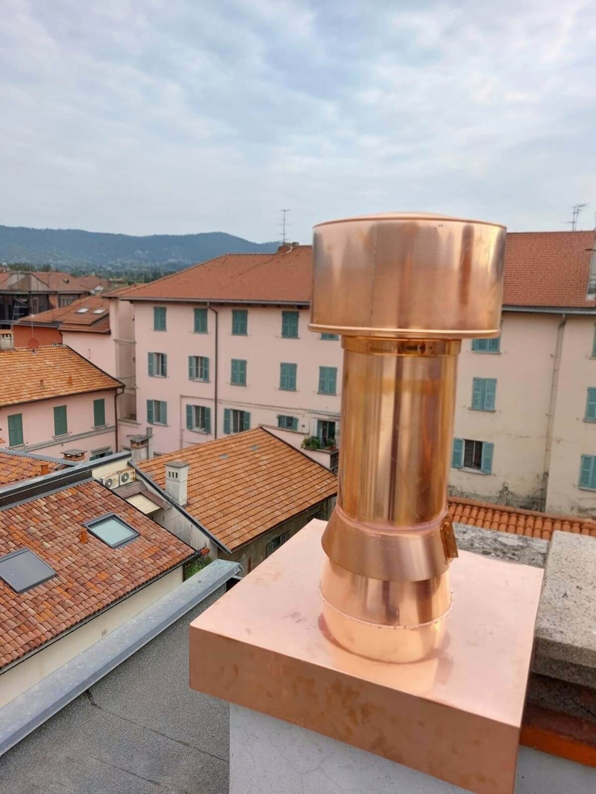 Un camino di rame in cima a un tetto con una città sullo sfondo