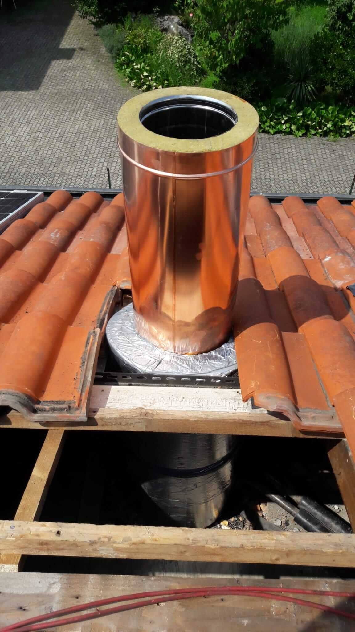 Un camino di rame è appoggiato su un tetto di tegole.