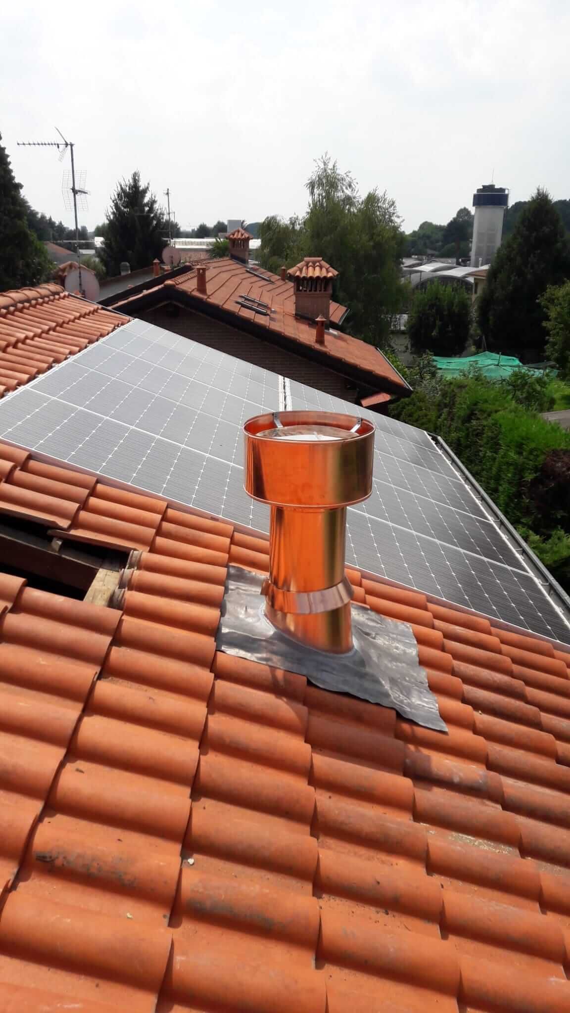 Un camino di rame è appoggiato su un tetto di tegole.