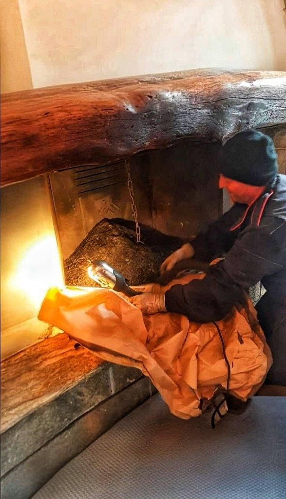 Spazzacamino mentre pulizie in camino con torcia in mano