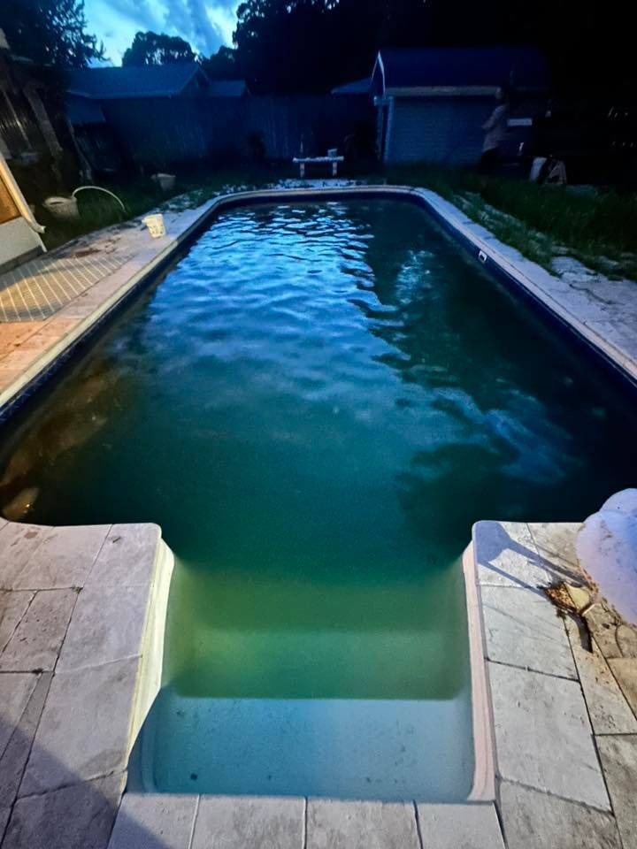 A rectangular pool with steps, filled with green-tinted water. The setting appears to be a backyard.