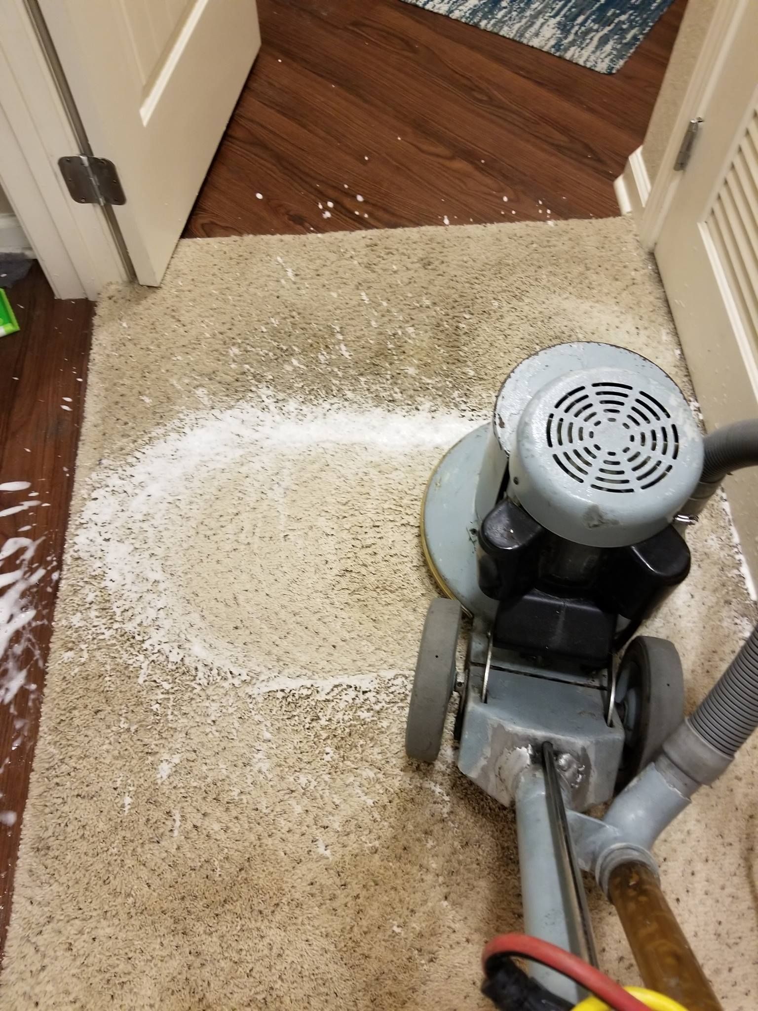 A machine is cleaning a carpet in a room.