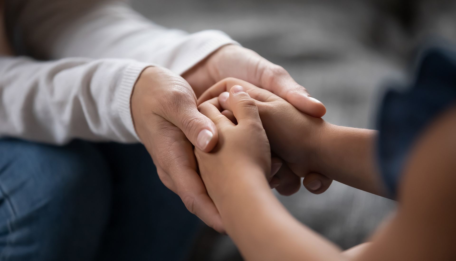 A woman is holding a child 's hand while sitting on a couch.