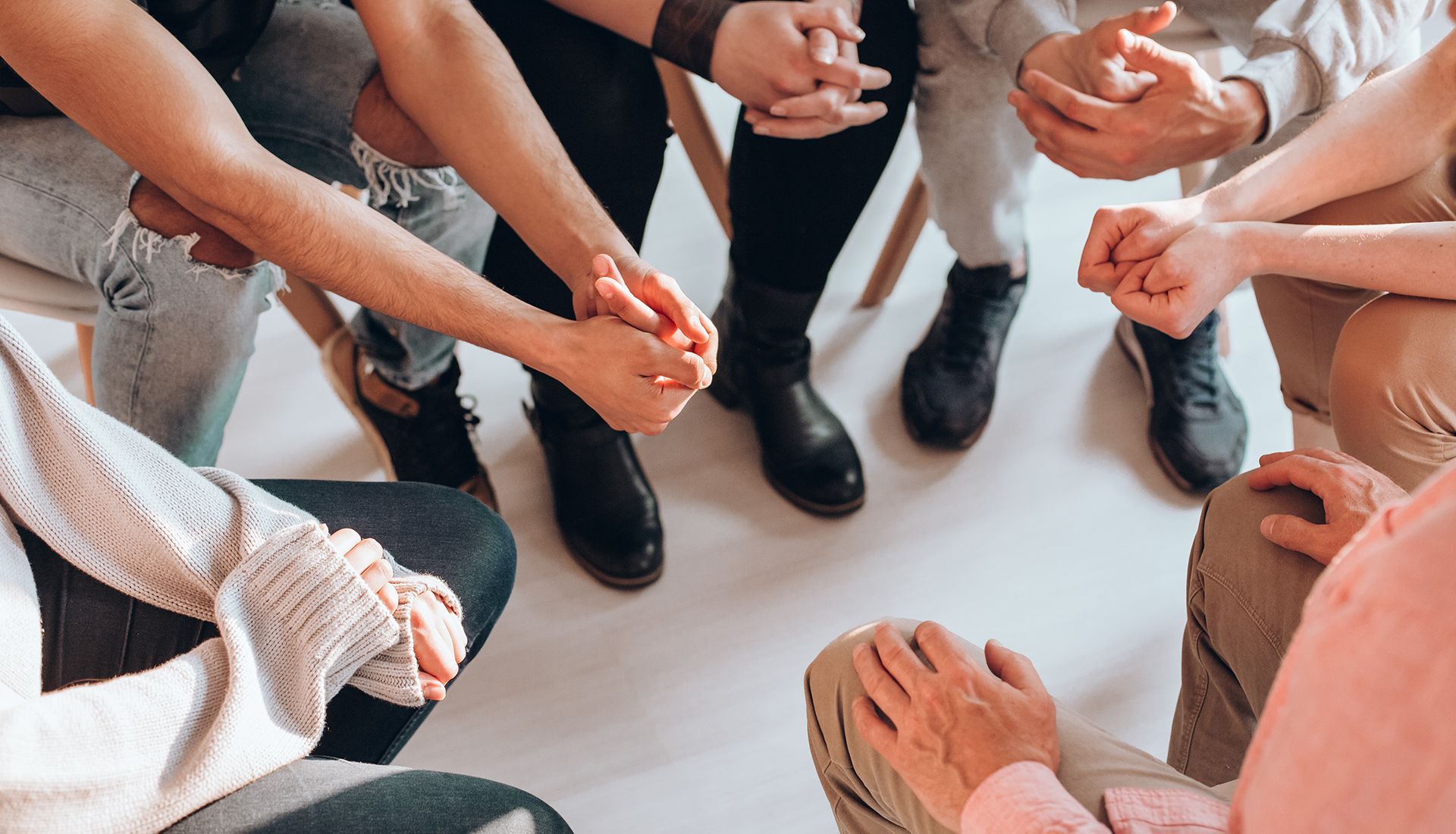 A group of people are sitting in a circle holding hands.