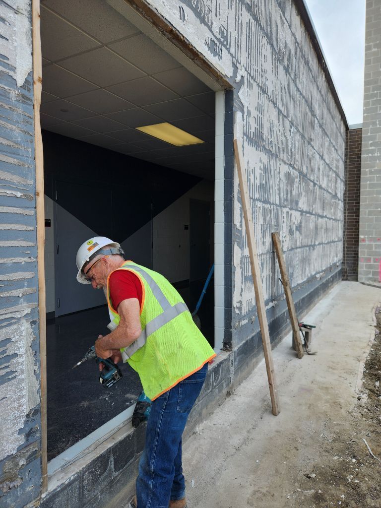 Worker in neon vest and hard hat measuring a doorway at a construction site