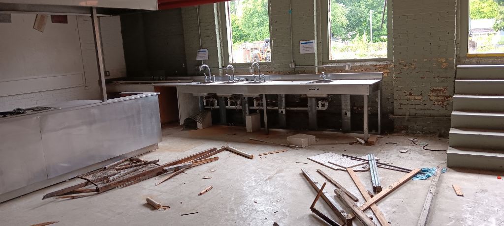 Unfinished room with exposed walls, debris on the floor, and a workbench by a window