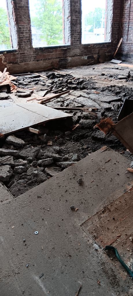 Damaged interior with debris-covered floor and broken walls near windows