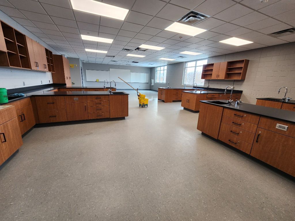 Empty science lab with wooden cabinets, black countertops, and bright ceiling lights