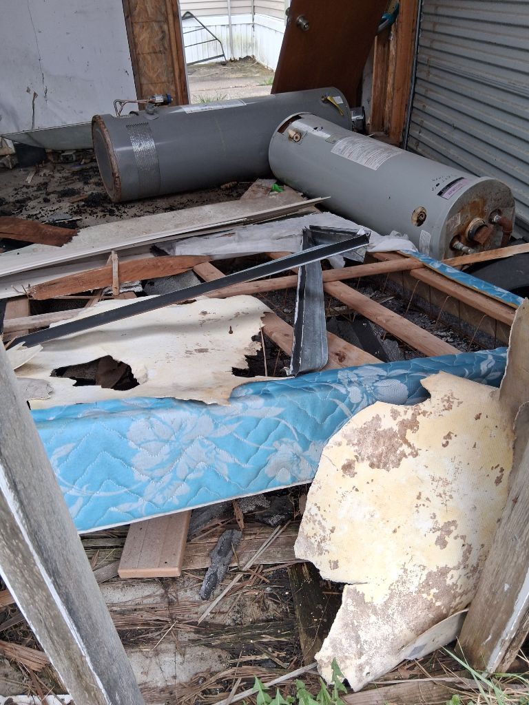Damaged metal cylinders and broken debris piled inside a cluttered, derelict shed