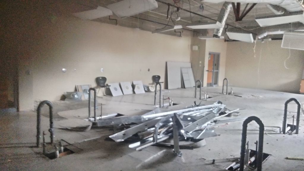 Empty industrial room with scattered metal debris and exposed ceiling beams.
