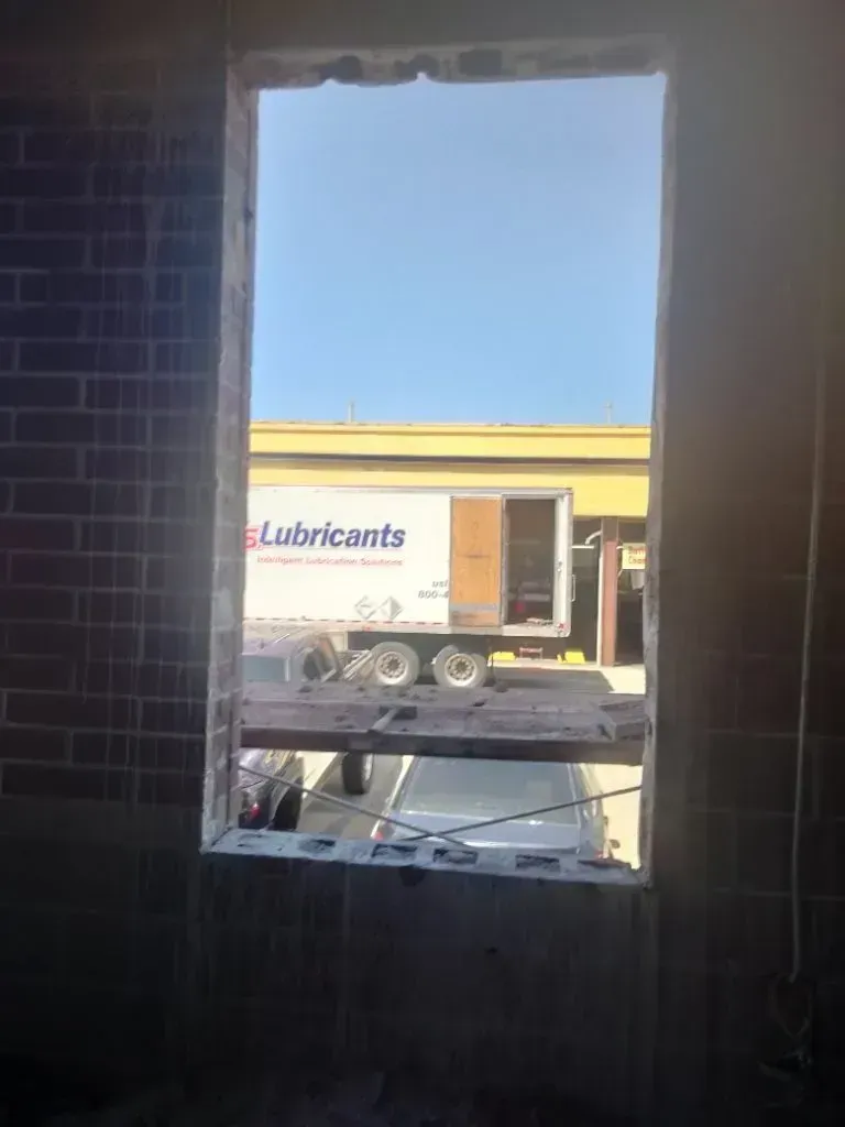 A view through an unfinished brick window frame showing a parked semi-truck with the word 