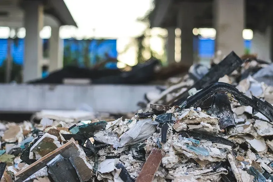 A close-up of a pile of construction rubble and debris in front of an unfinished building structure.
