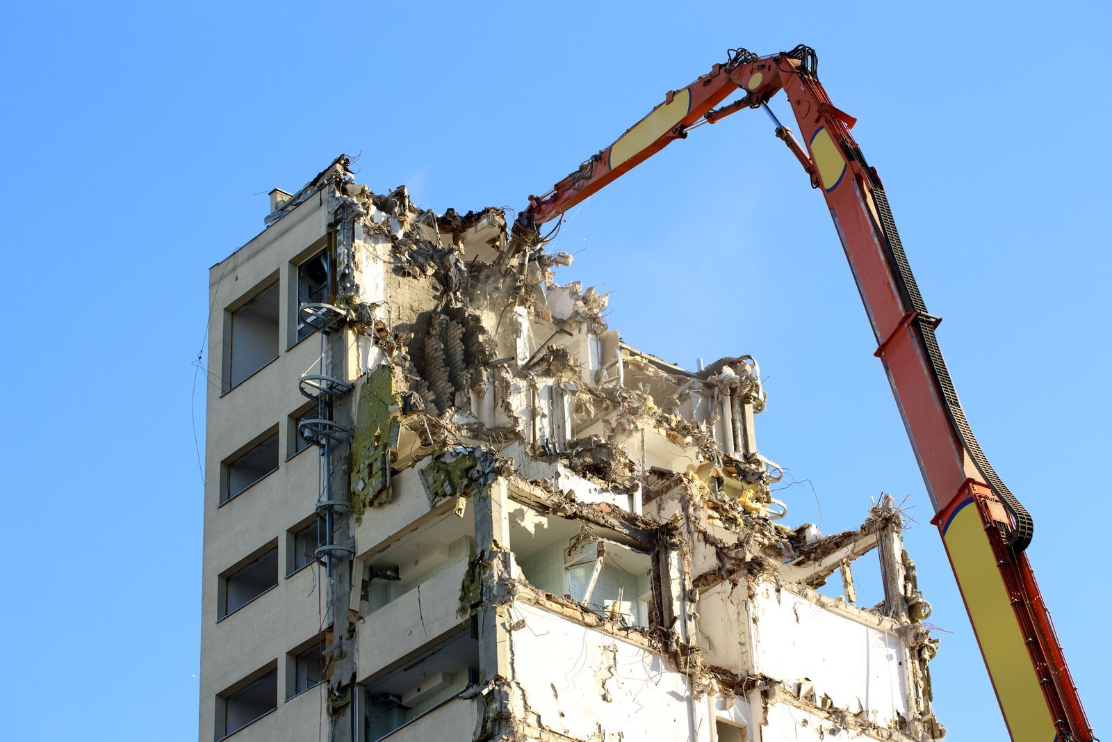A large building is being demolished by a crane.